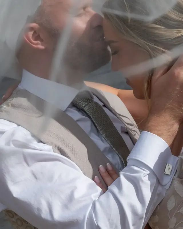 Groom kissing his bride's forehead through the veil