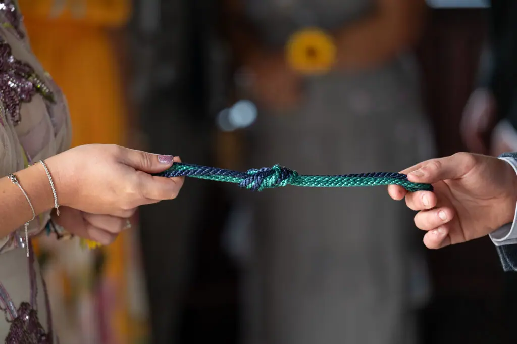 Handfasting ribbon being tied around the couple's hands