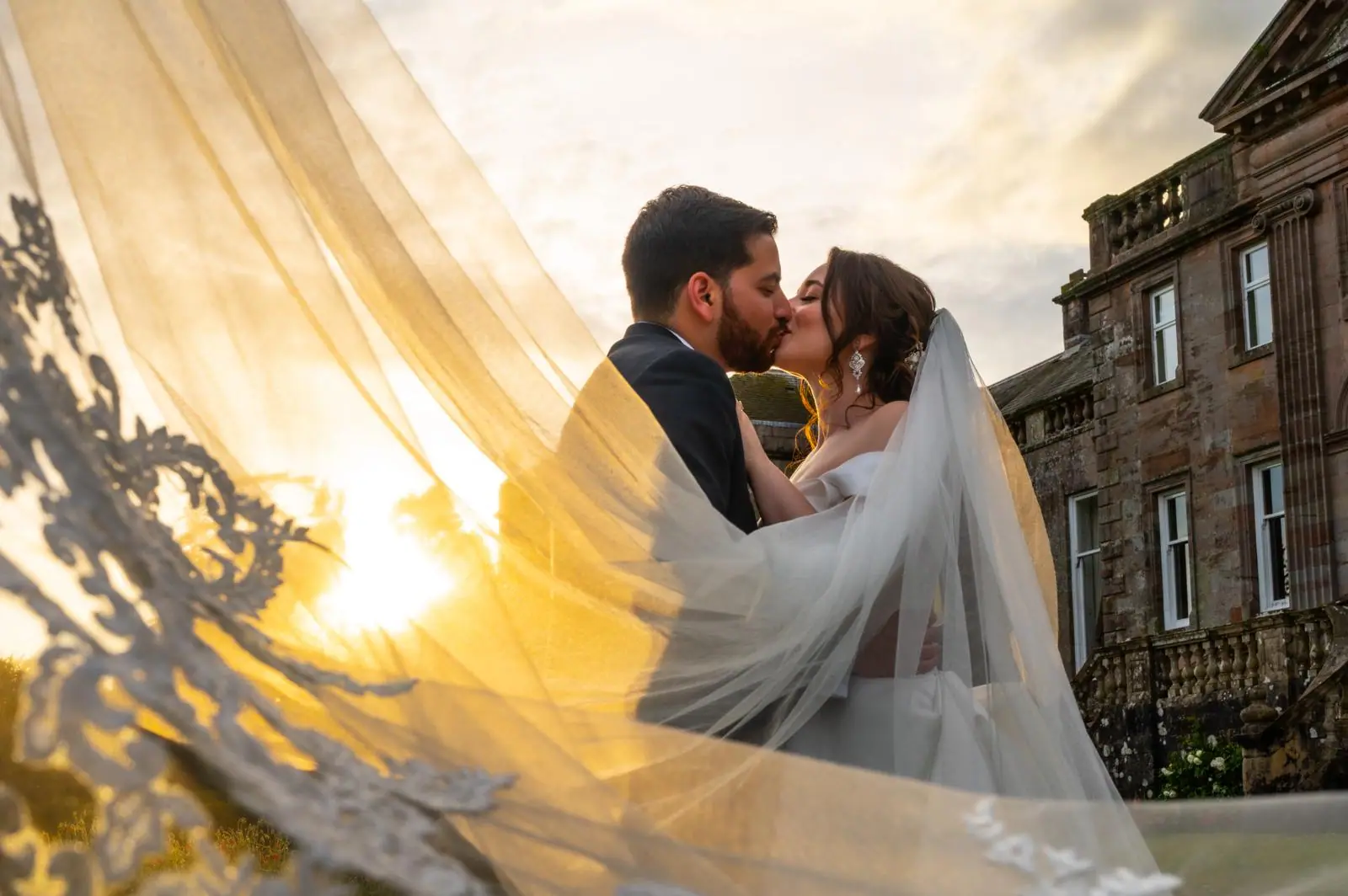 Couple kissing beneath a sunlit veil