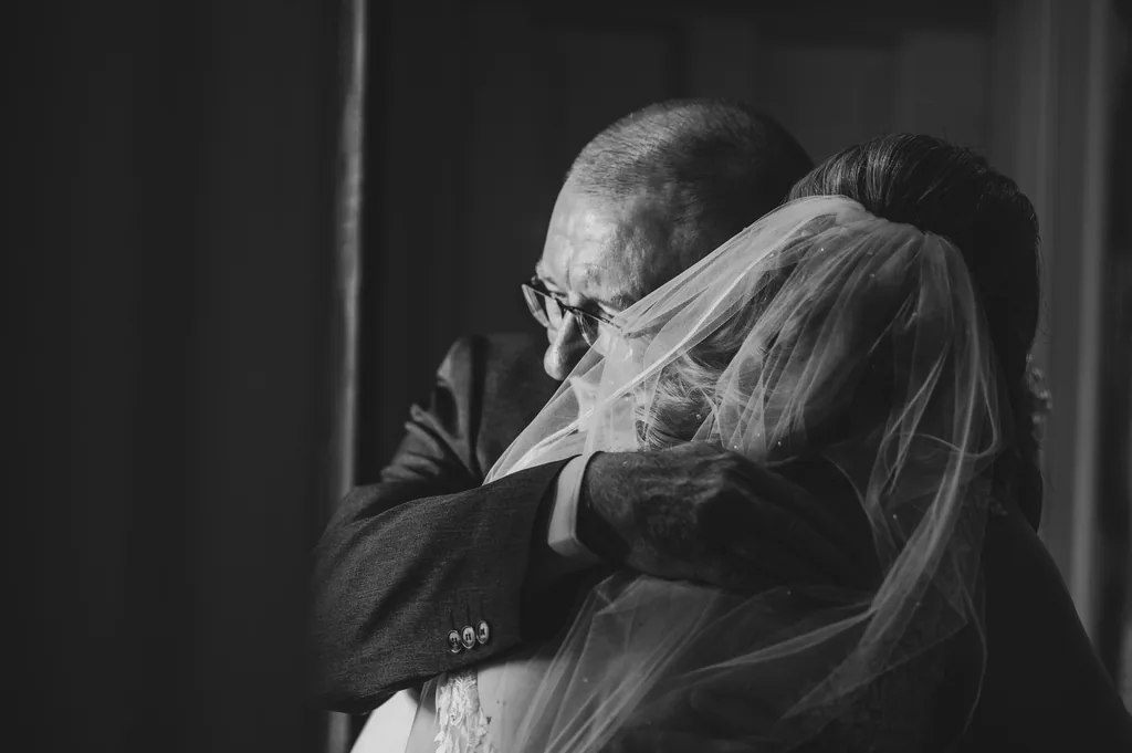 Black-and-white close-up of a father hugging the bride on her wedding day