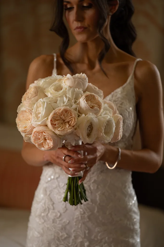 Close-up of a bride holding a bouquet of white and blush roses