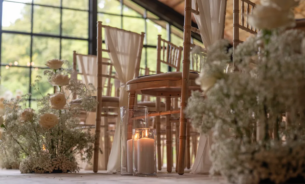 Candlelit wedding ceremony room with wooden chairs and draped windows