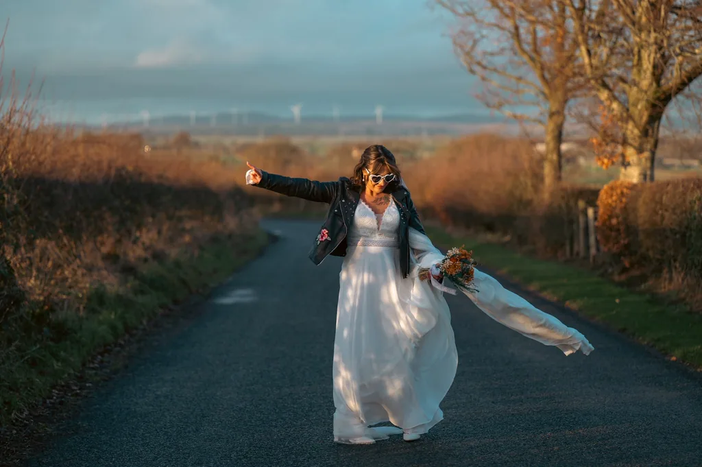 Bride on a country lane with her veil blowing in the wind